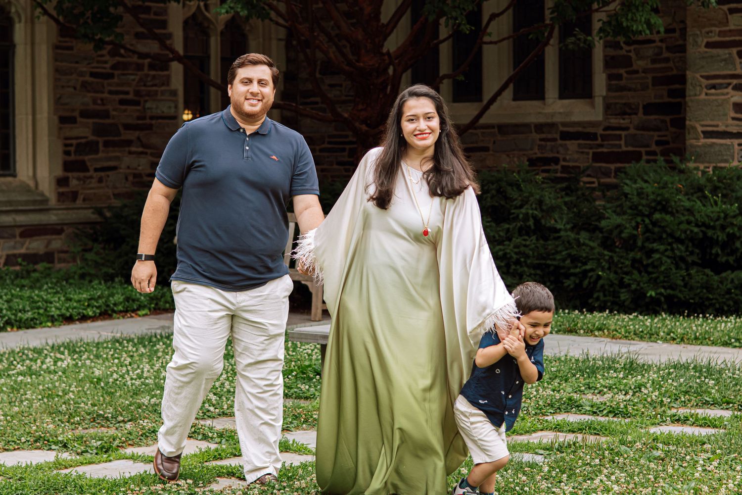 A happy family holding hands and walking together outdoors through the scenic campus grounds at Princeton University in New Jersey.