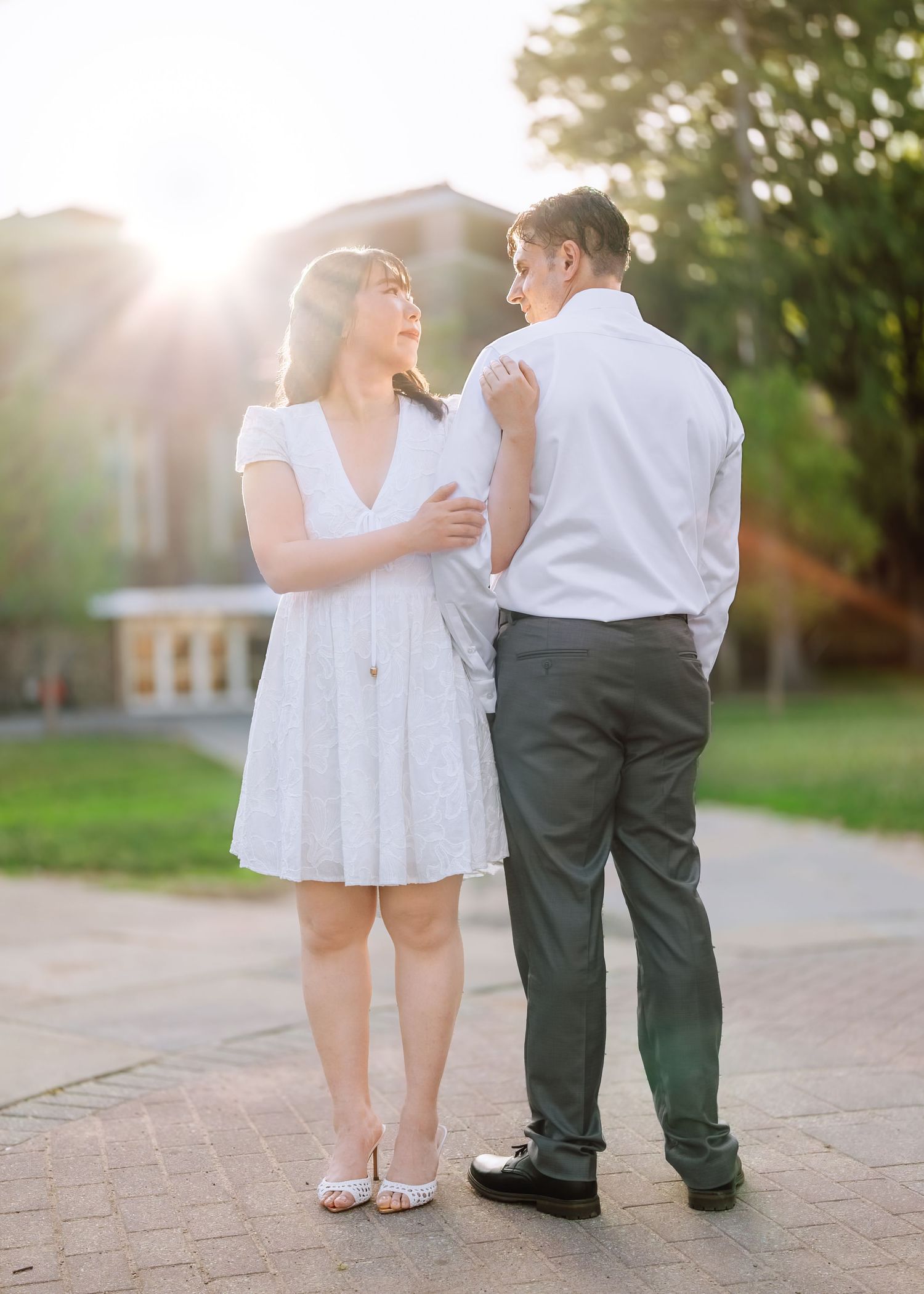 An engaged couple holding hands and walking along a stone path in front of a historic gothic-style building at Princeton University.