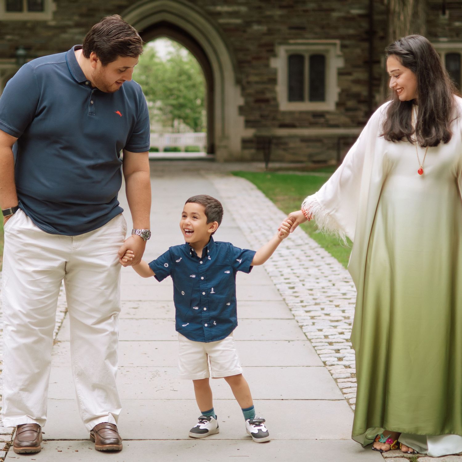 A happy family holding hands and walking together outdoors through the scenic campus grounds at Princeton University in New Jersey.