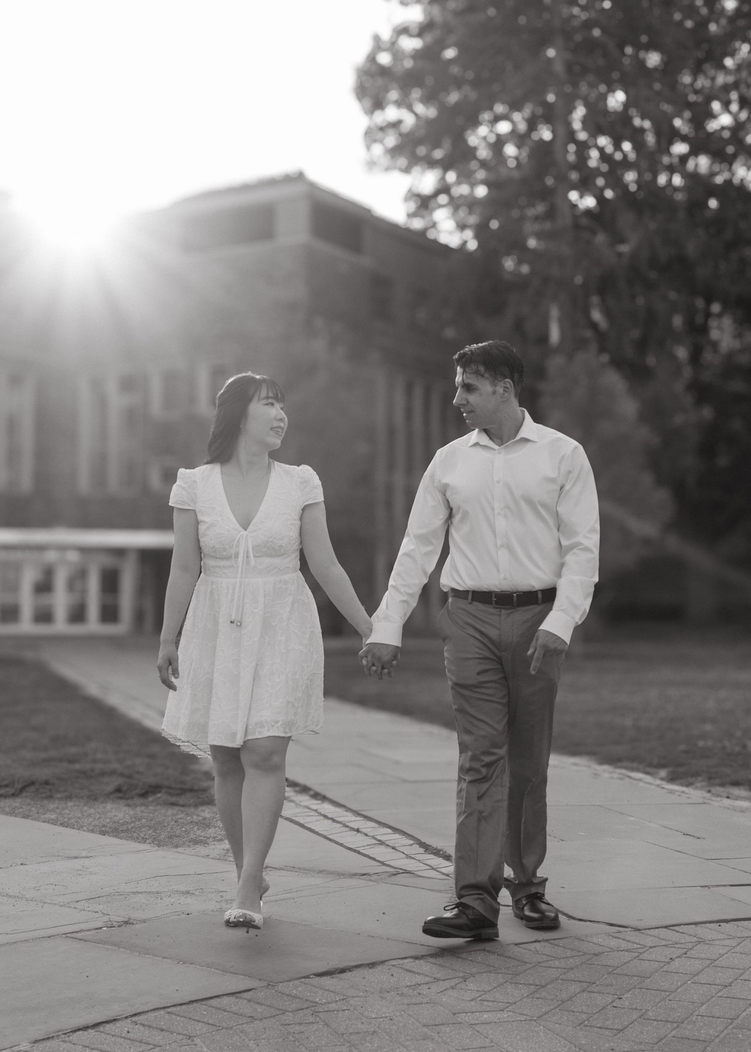 A couple holding hands and smiling while walking near the historic gothic architecture on the Princeton University campus in New Jersey.