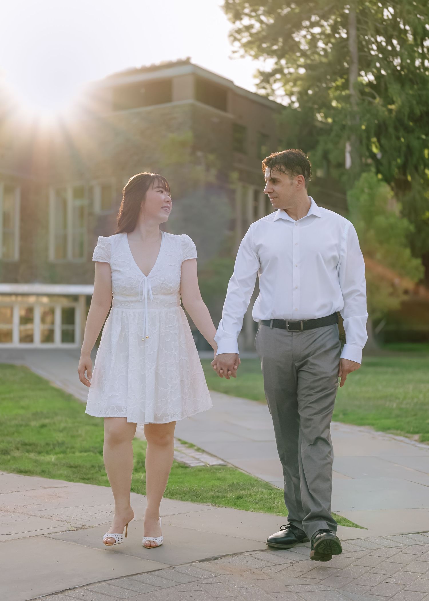 A couple holding hands and smiling while walking near the historic gothic architecture on the Princeton University campus in New Jersey.