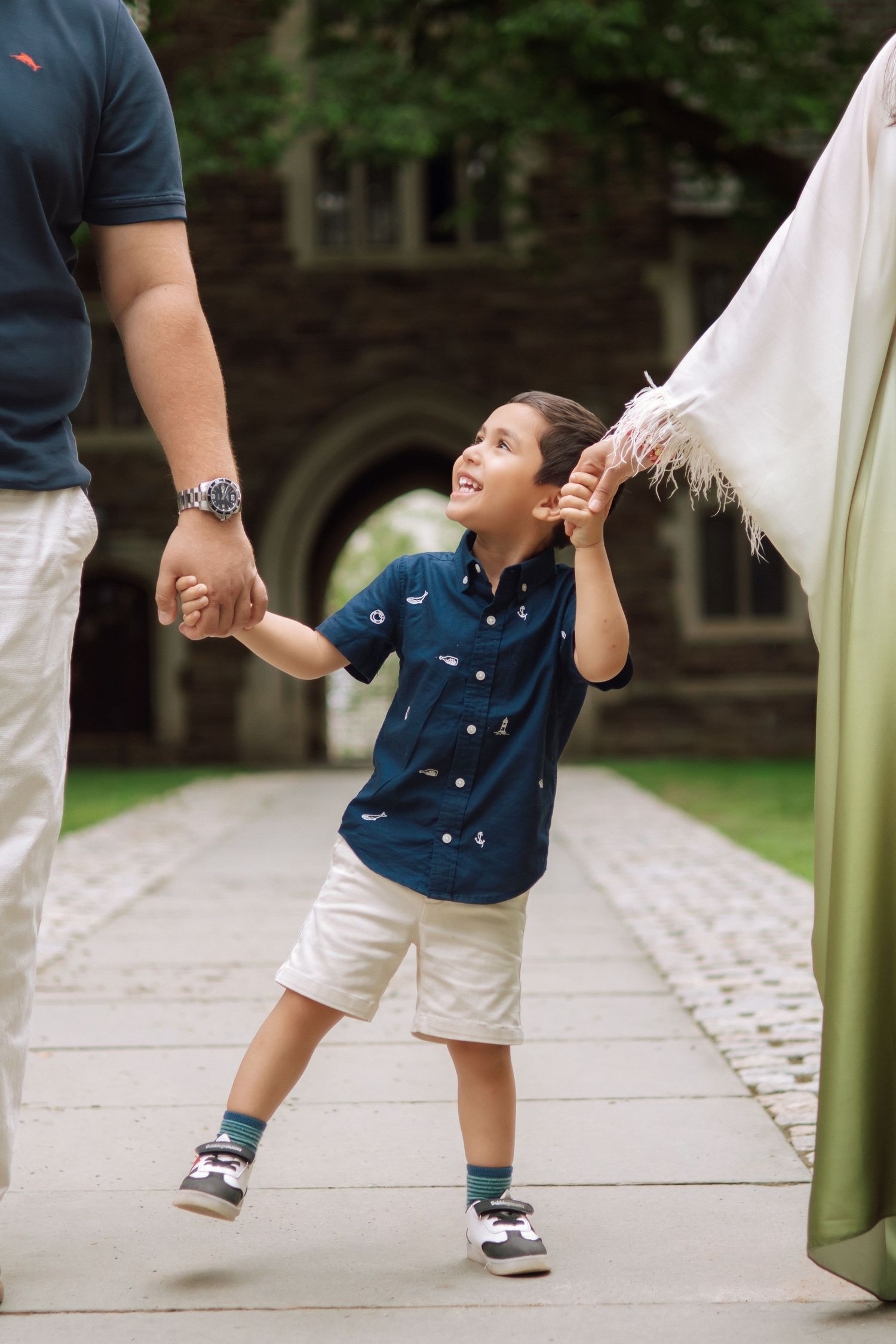 A happy family holding hands and walking together outdoors through the scenic campus grounds at Princeton University in New Jersey.