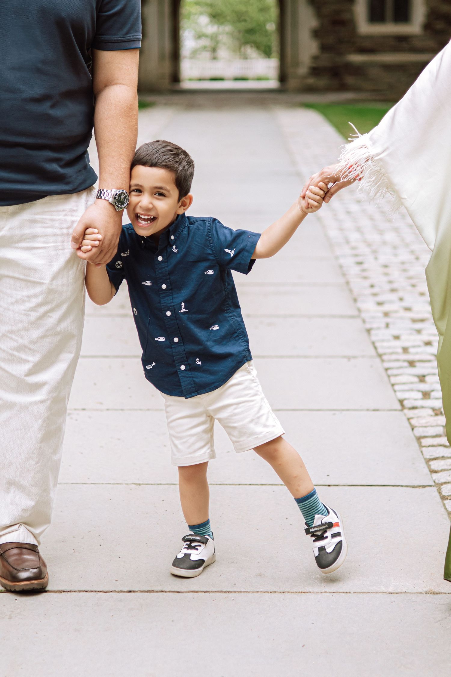 A happy family holding hands and walking together outdoors through the scenic campus grounds at Princeton University in New Jersey.