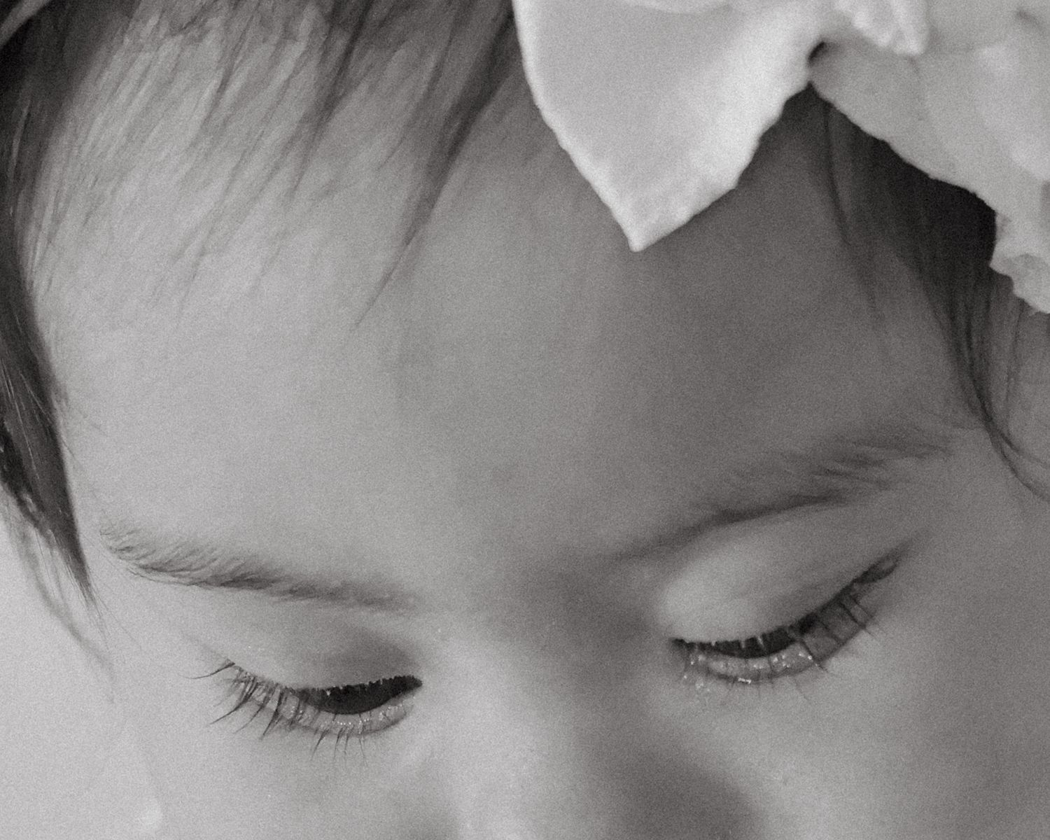 A baby girl celebrating her first birthday, wearing a white tulle dress and sitting on a blanket outdoors in a studio indoors.