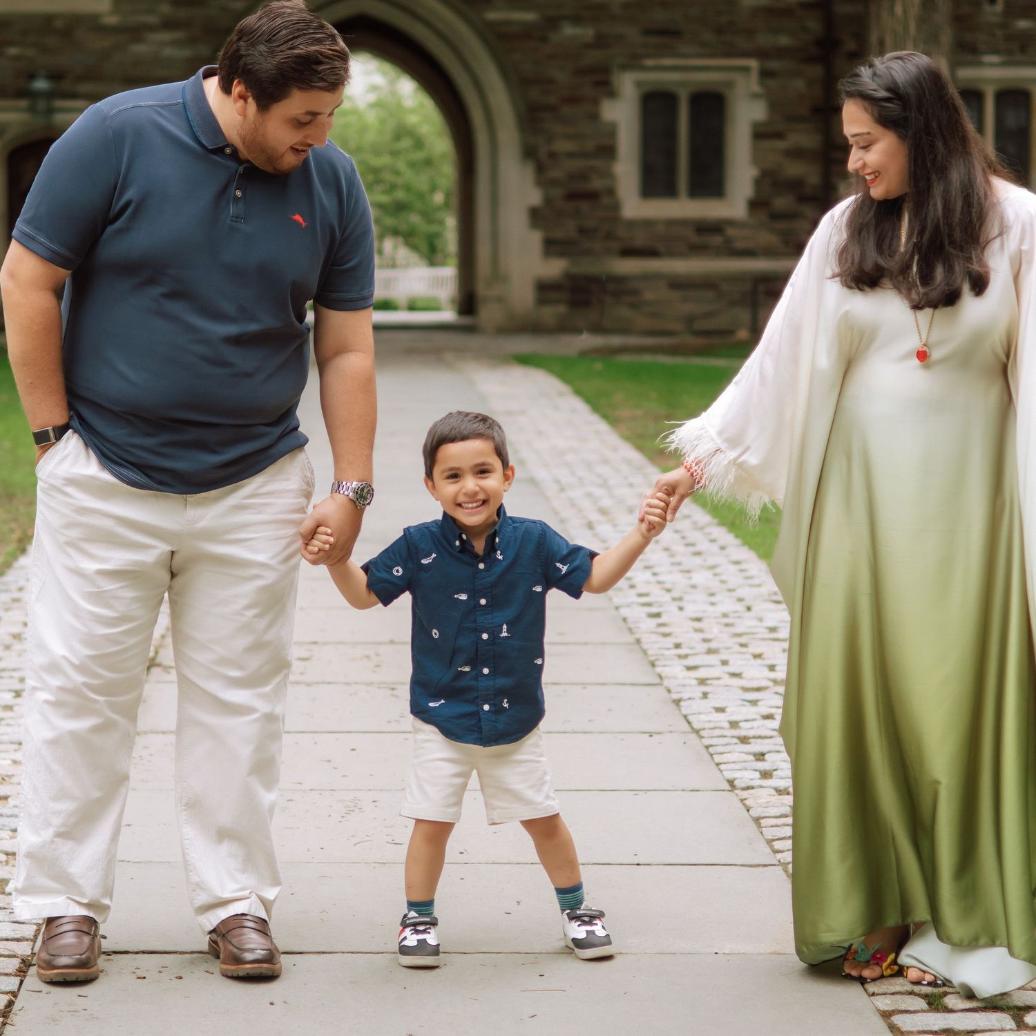 A happy family holding hands and walking together outdoors through the scenic campus grounds at Princeton University in New Jersey.