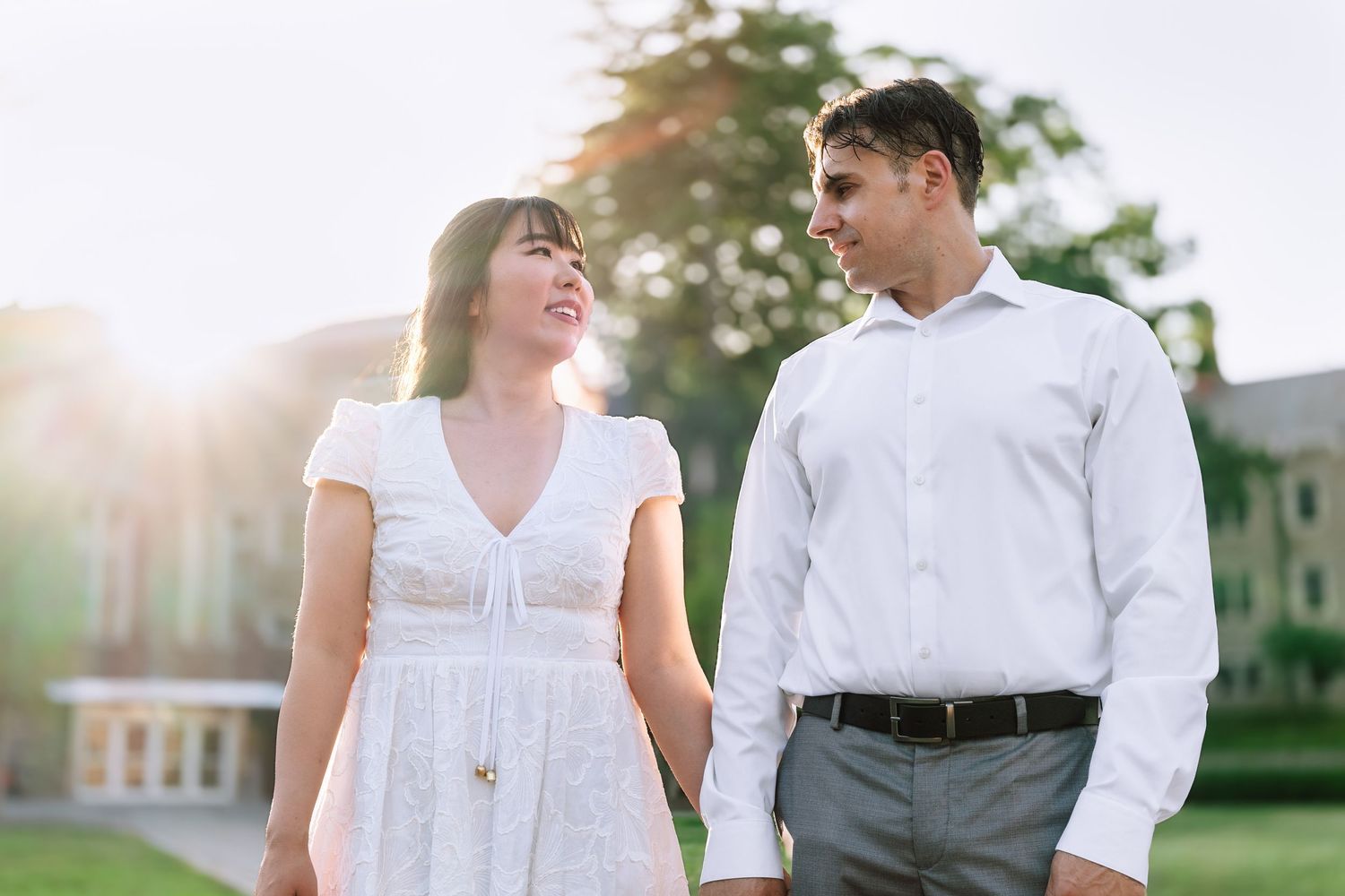 A couple holding hands and smiling while walking near the historic gothic architecture on the Princeton University campus in New Jersey.