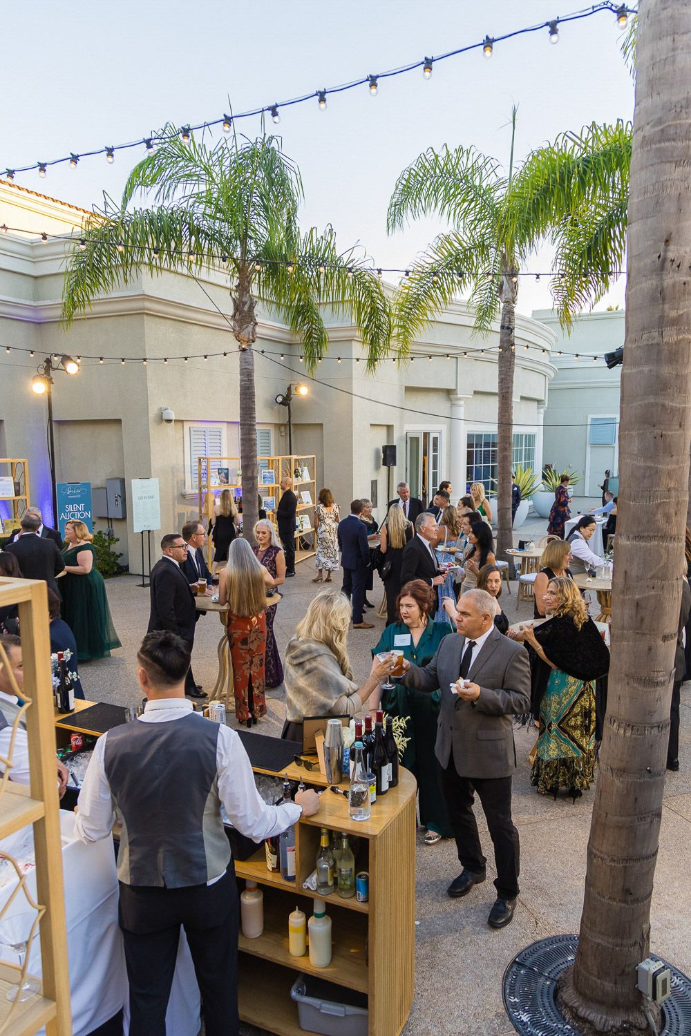 Outdoor daytime corporate event reception with palm trees.