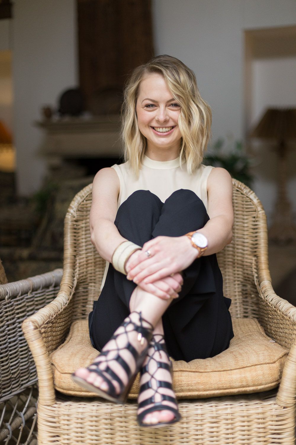 Playful natural light portraits of a blond woman with here arms wrapped around her knees.