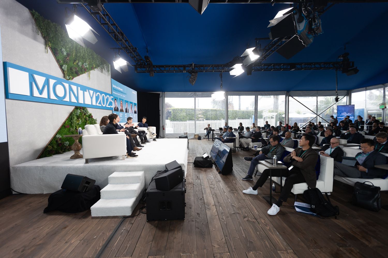Wide shot of panel speakers with audience at a corporate summit.