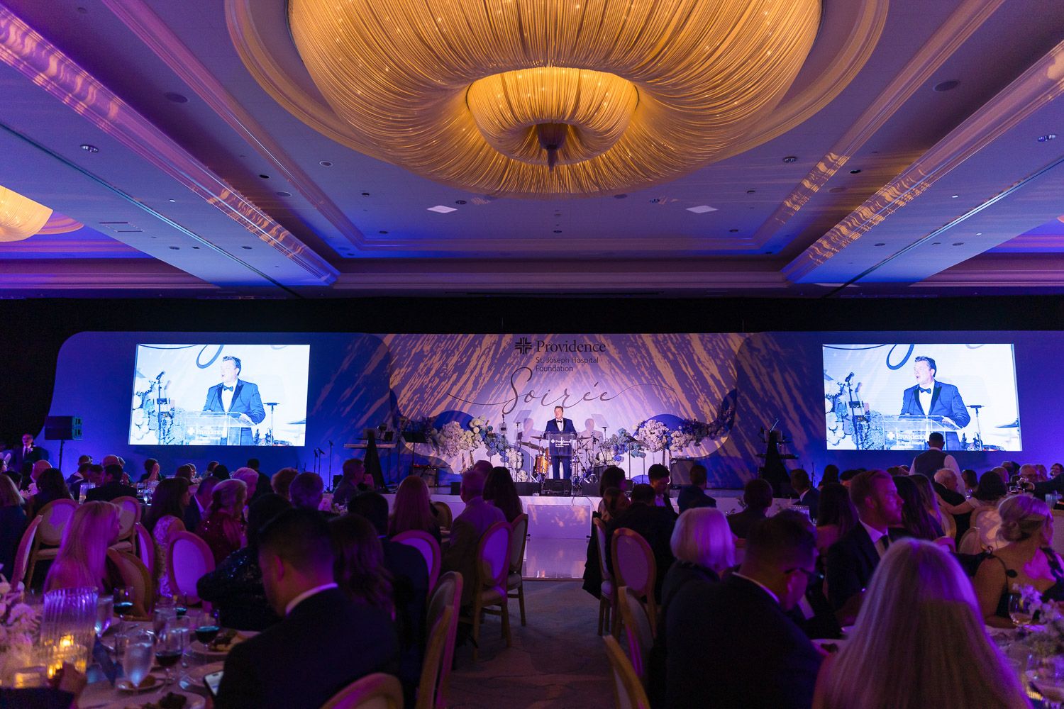 Wide view of ballroom stage presentation at a gala.