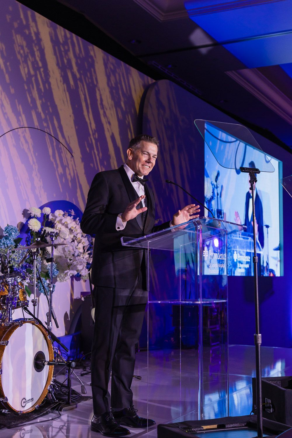 Presenter speaking on stage at a corporate event gala.
