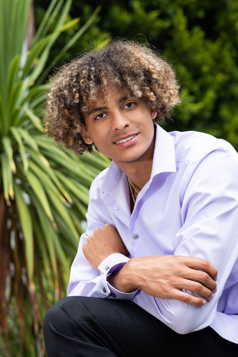 Casual professional headshot portrait of a young man in a light purple button down shirt.