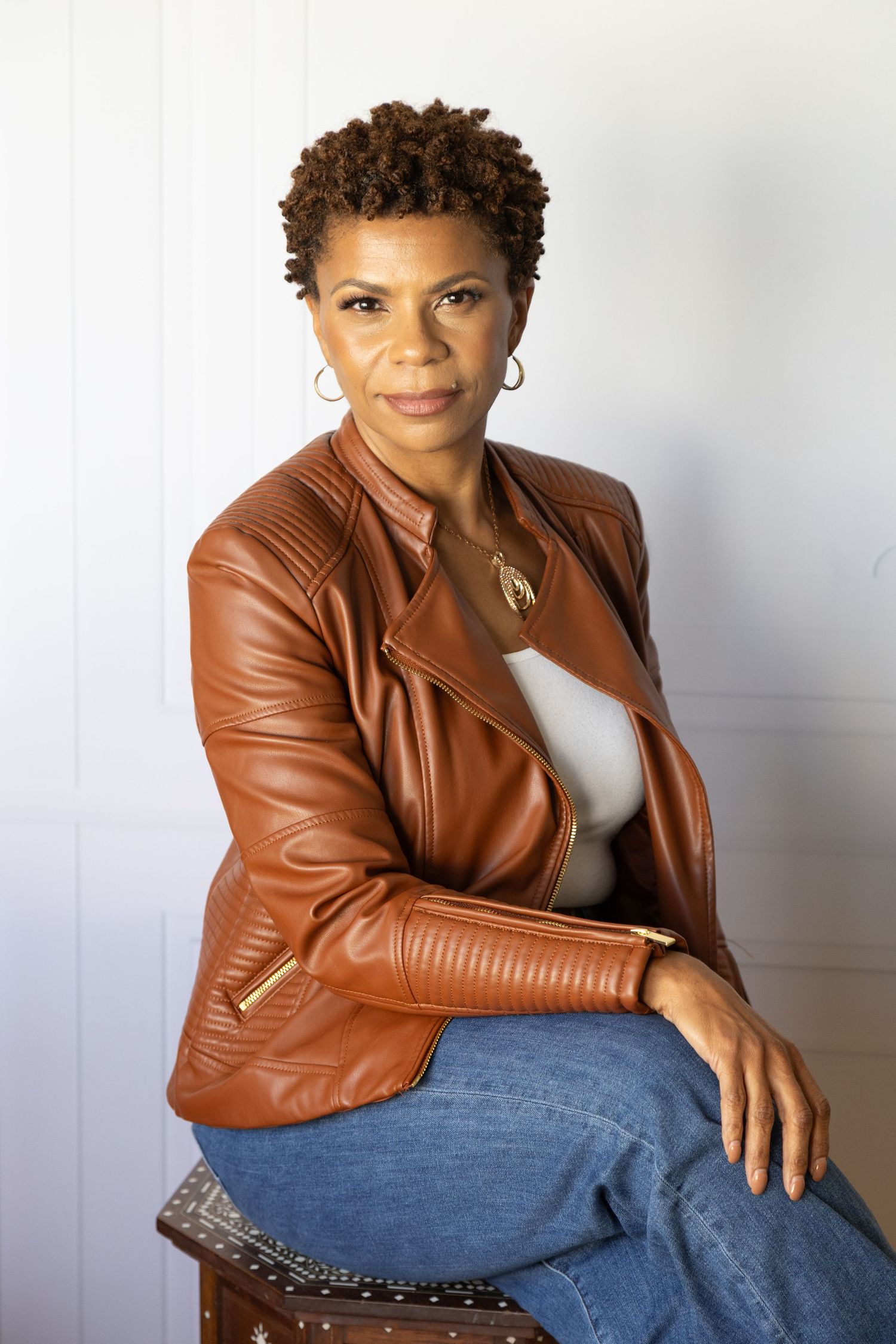 Studio headshot of a woman wearing a stylish brown leather jacket.