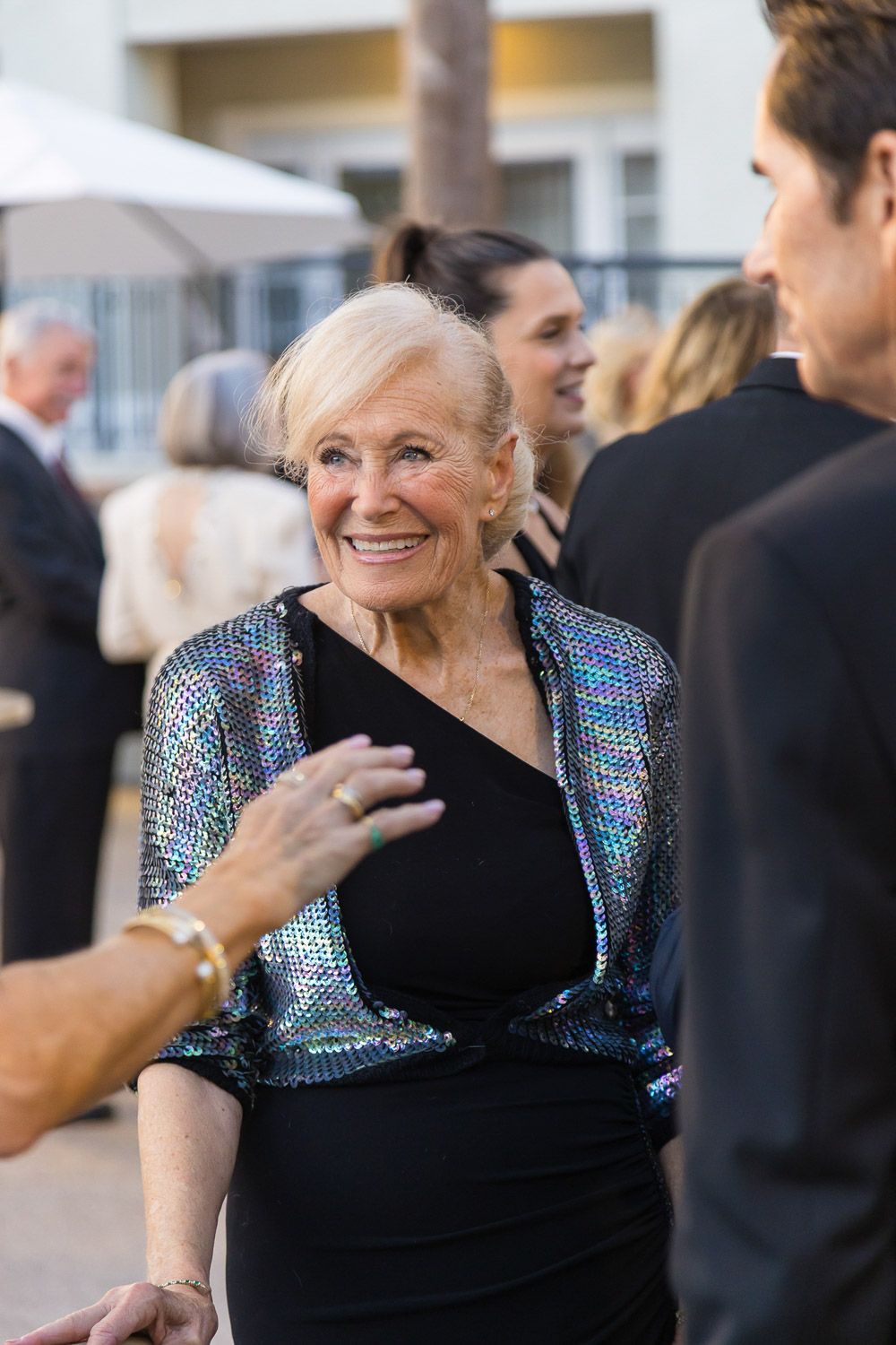 Smiling woman talking with quests at corporate gala dinner.