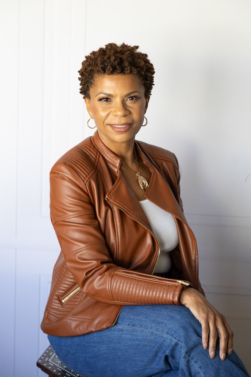 Studio headshot of a woman wearing a stylish brown leather jacket.