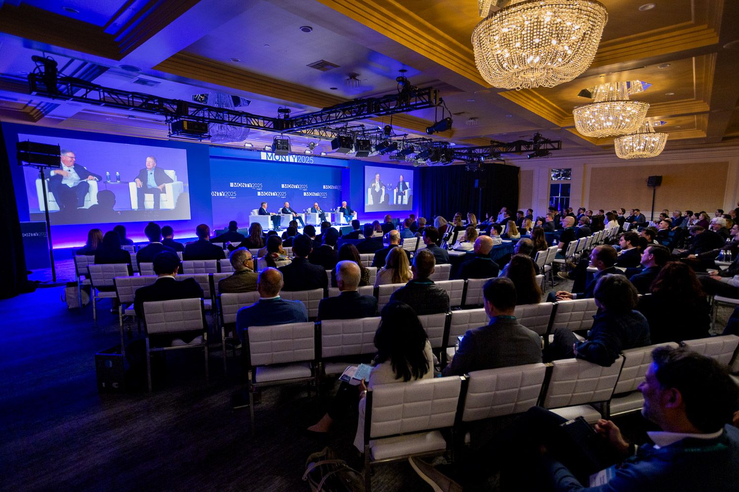 Dimly lit ballroom filled with quests for a corporate presentation.