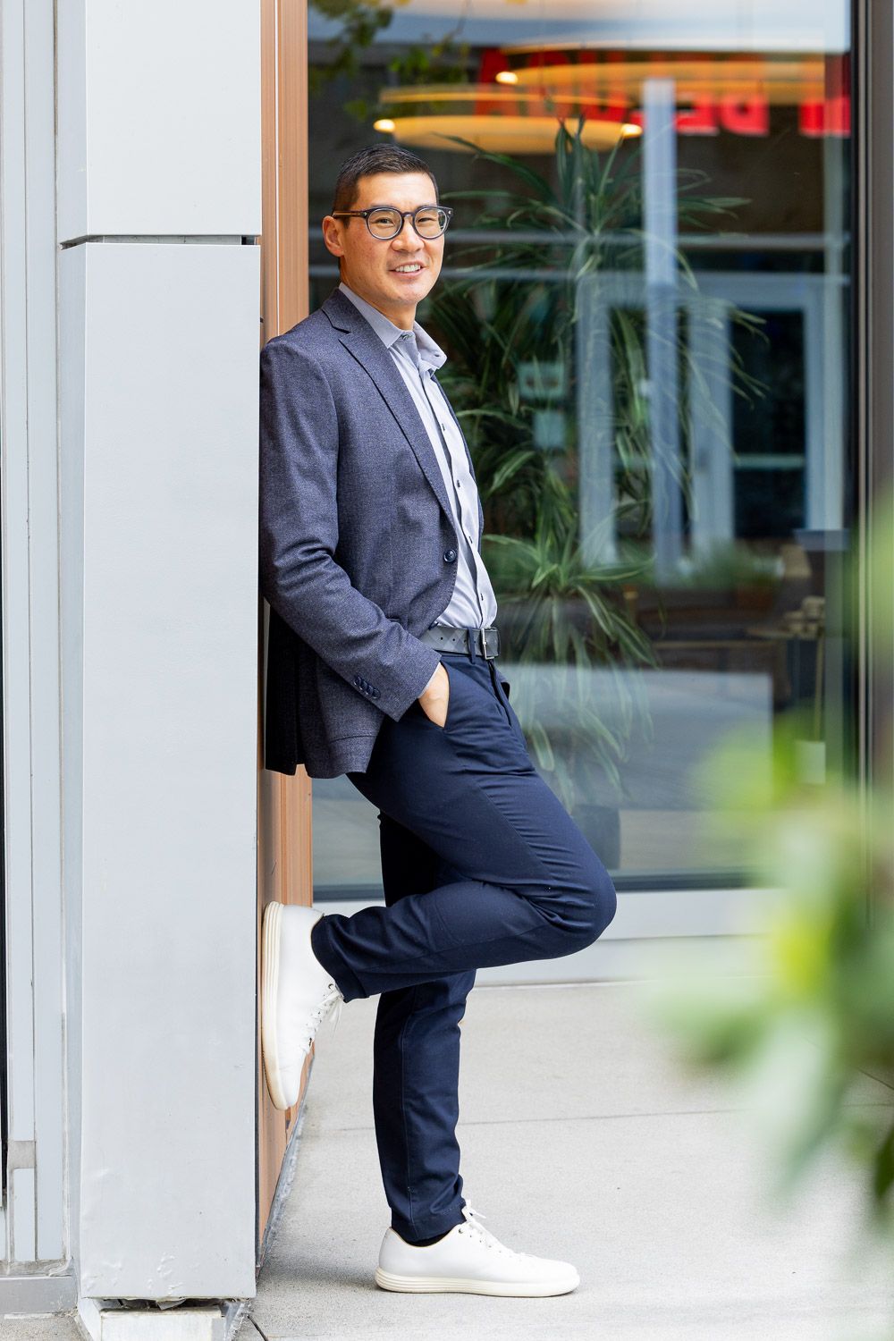 Modern professional shot of a man leaning against an office building outdoor.