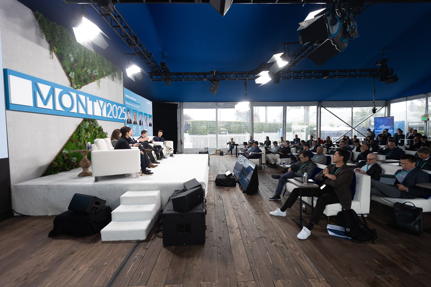 Wide room shot of a speaking panel on stage and the audience.