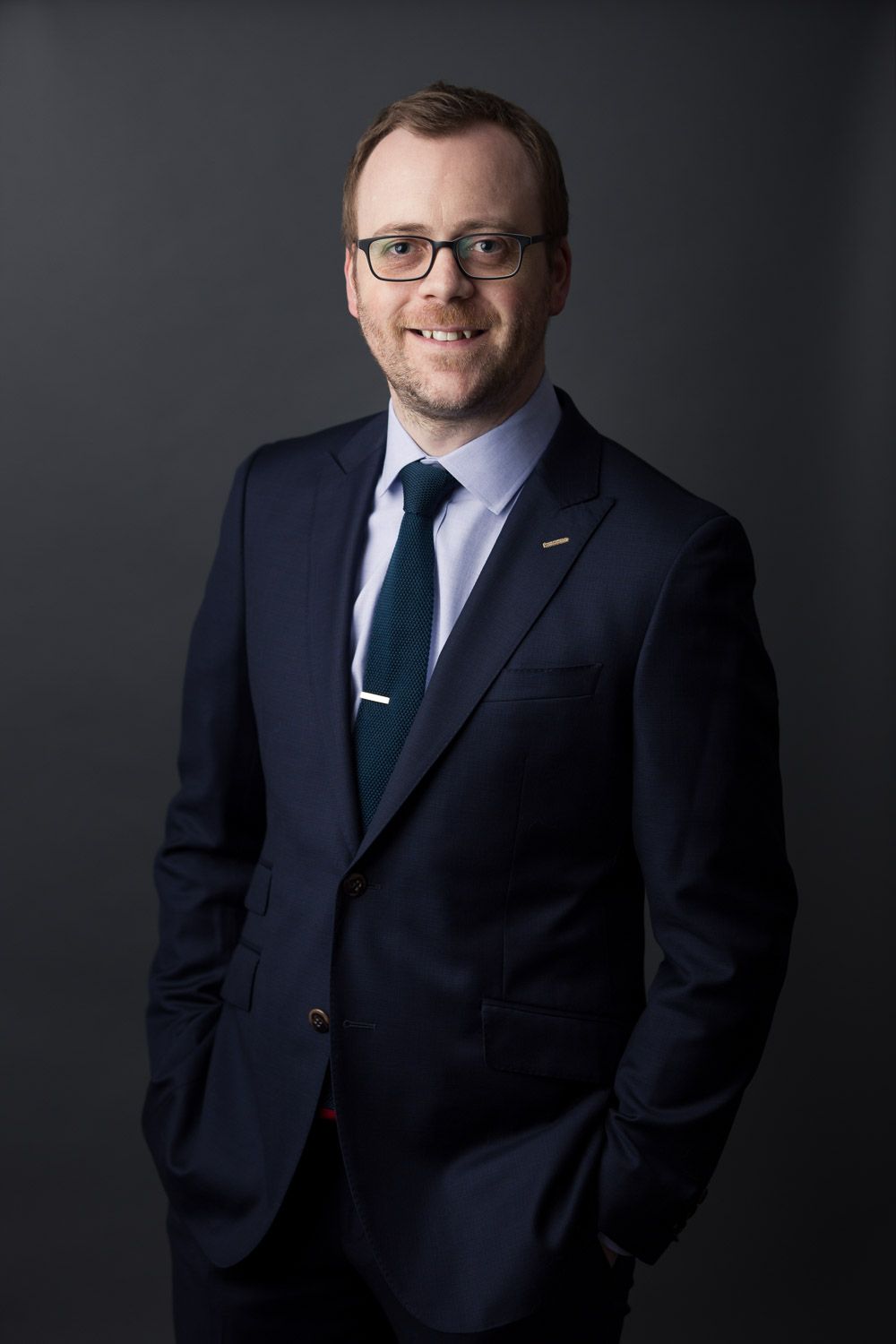 Classic corporate headshot of a businessman in a formal dark suit and tie.