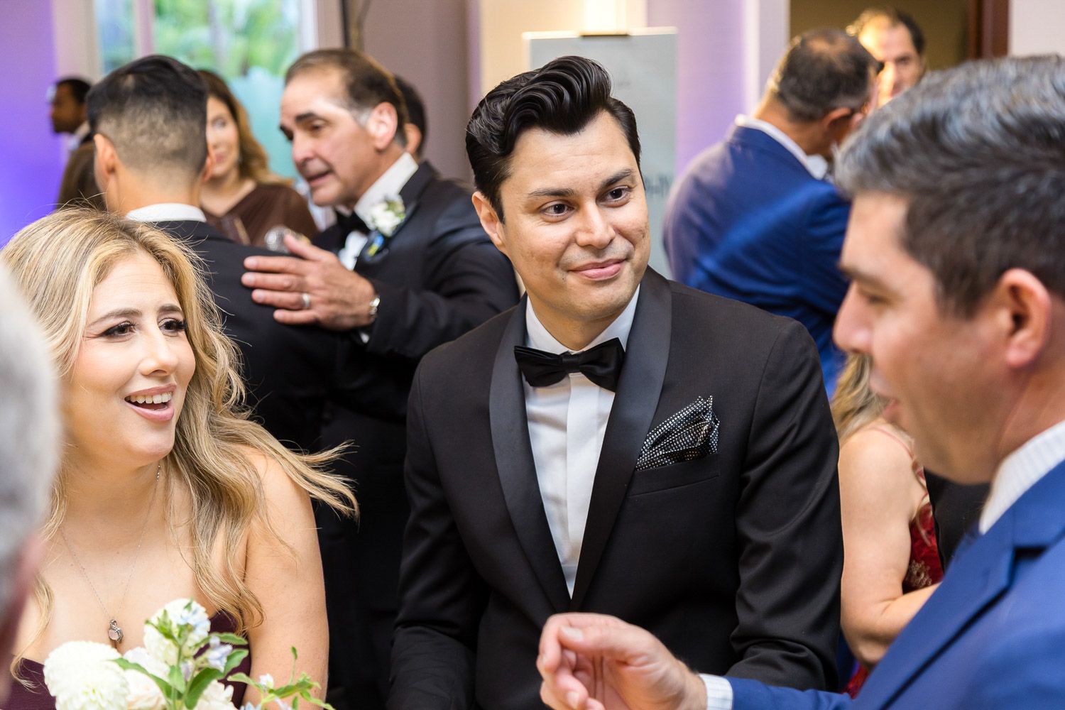 Group of corporate gala guests talking and laughing at cocktail reception.