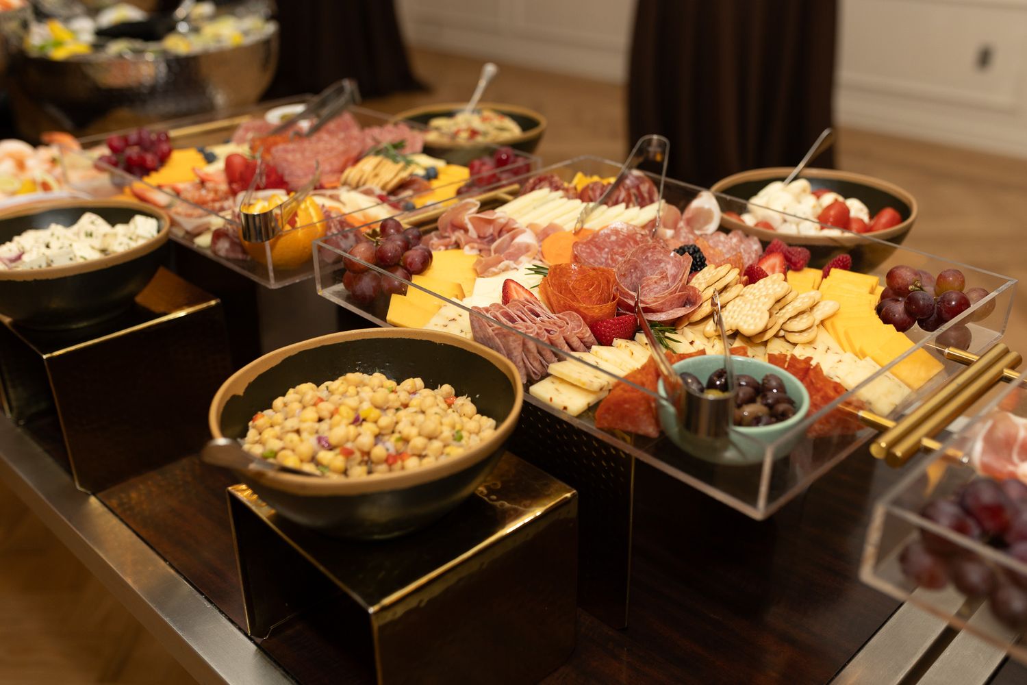 This image features a lavish grazing table with a variety of foods, including charcuterie, fruit, and what appears to be nuts or small snack