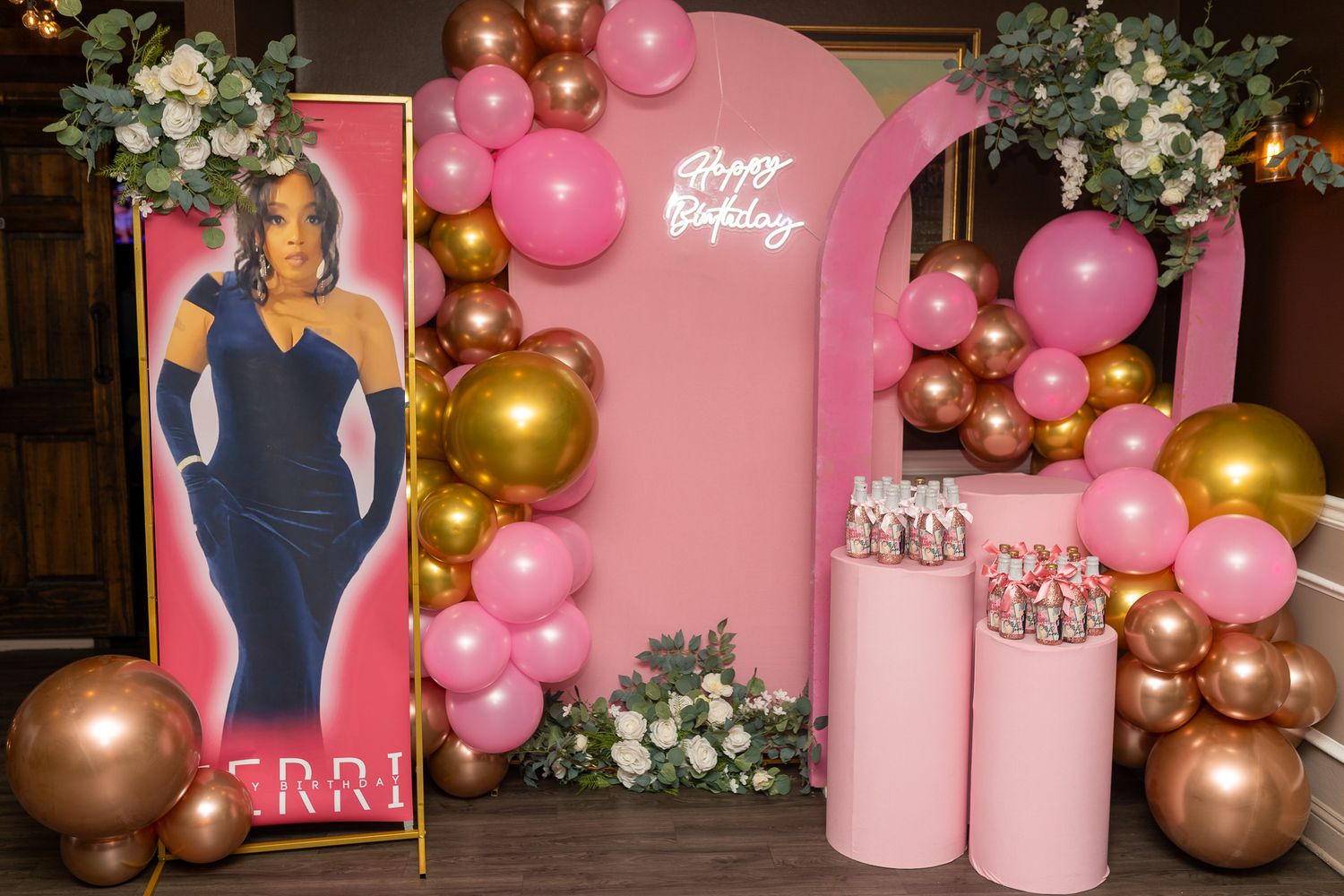 a pink and gold birthday display. It includes a large cutout of a woman in a blue dress, a 