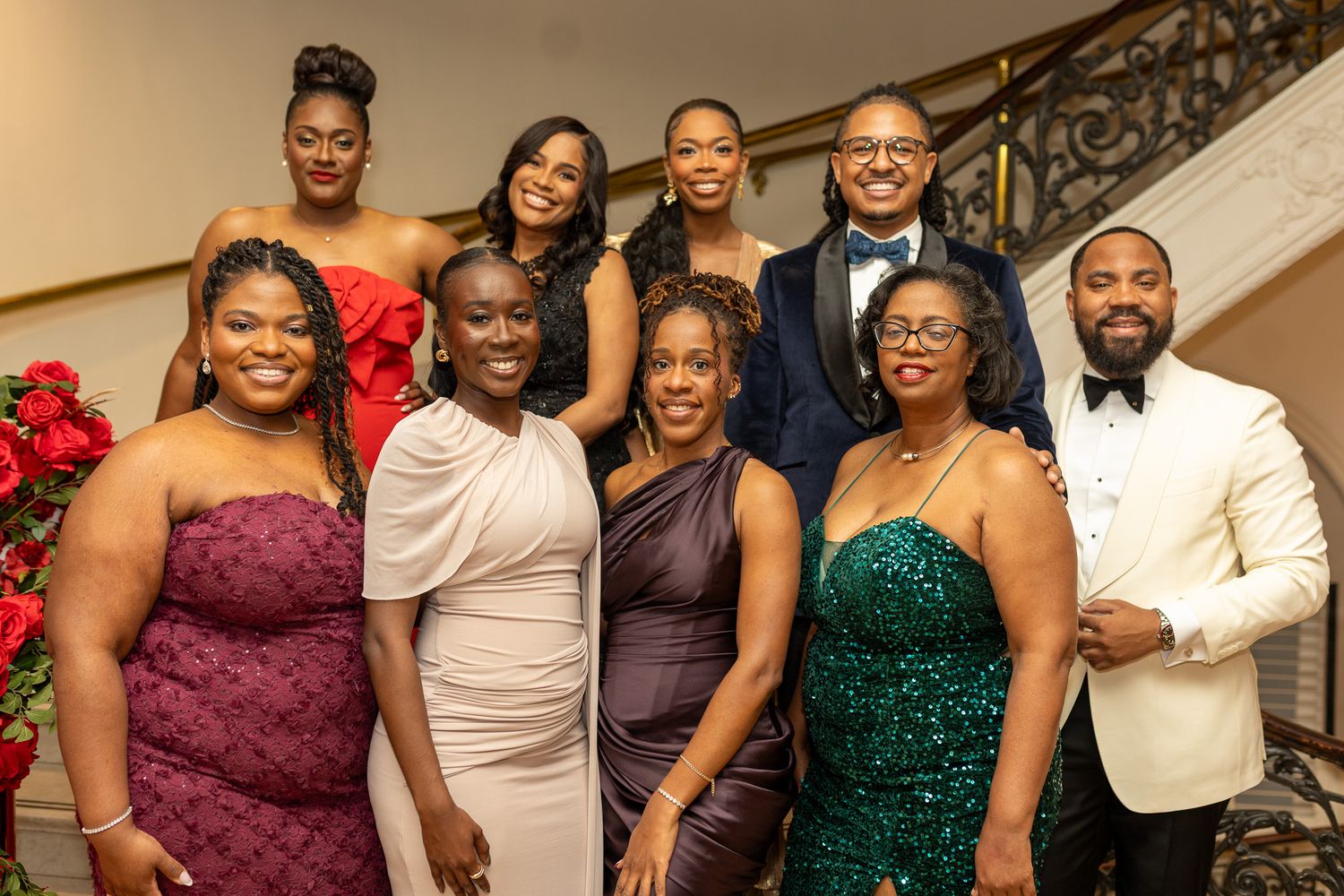 This image shows a group of seven people posing together indoors, likely at a formal event. They are dressed in formal attire.