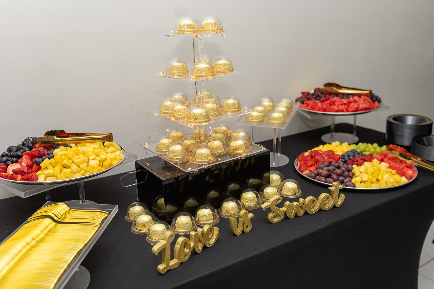 a dessert table with a multi-tiered tower of gold-wrapped treats, possibly cake pops or chocolates, as the centerpiece.