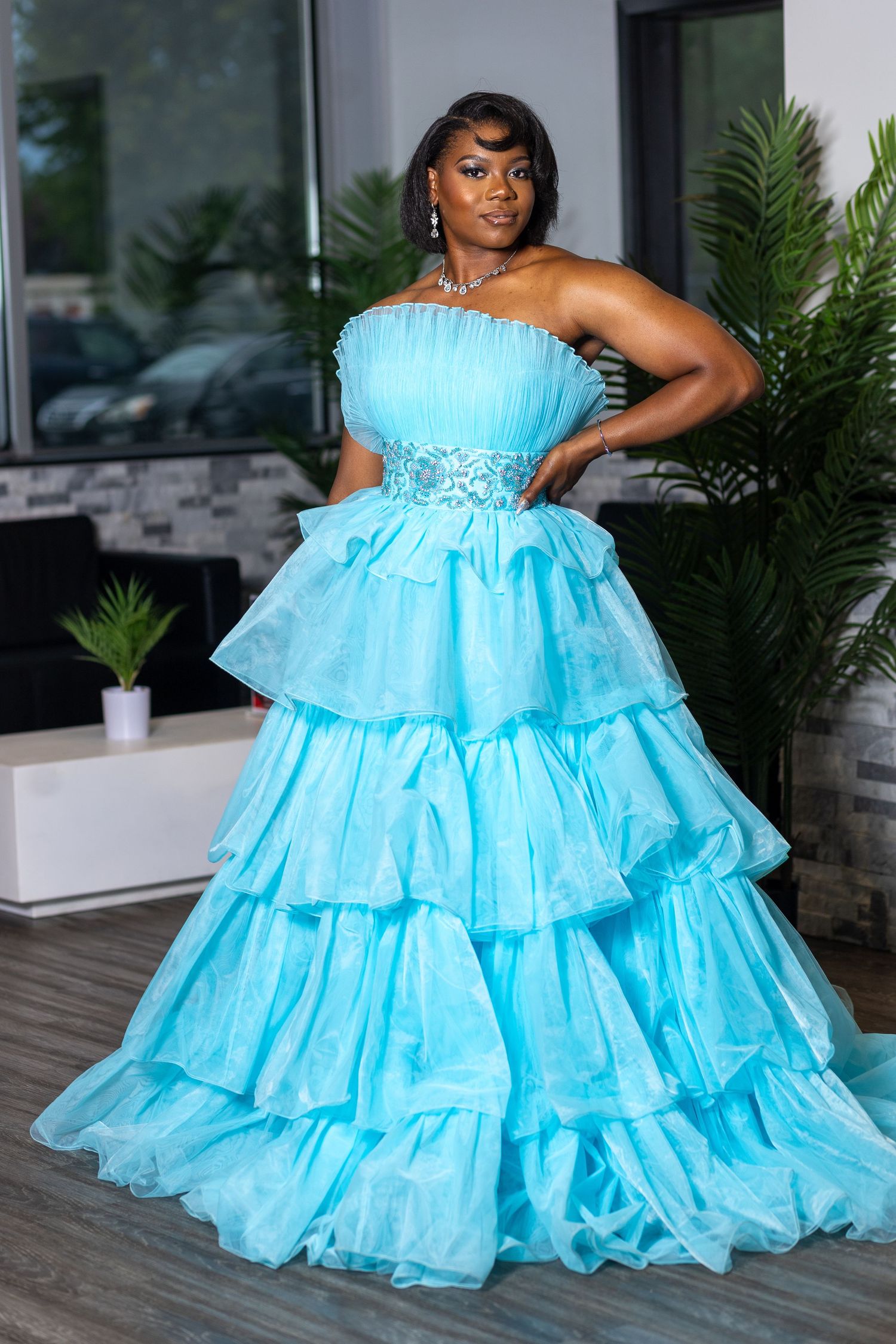 a woman standing and posing in a strapless, tiered, light blue tulle prom gown. This a a prom sendoff photoshoot.
