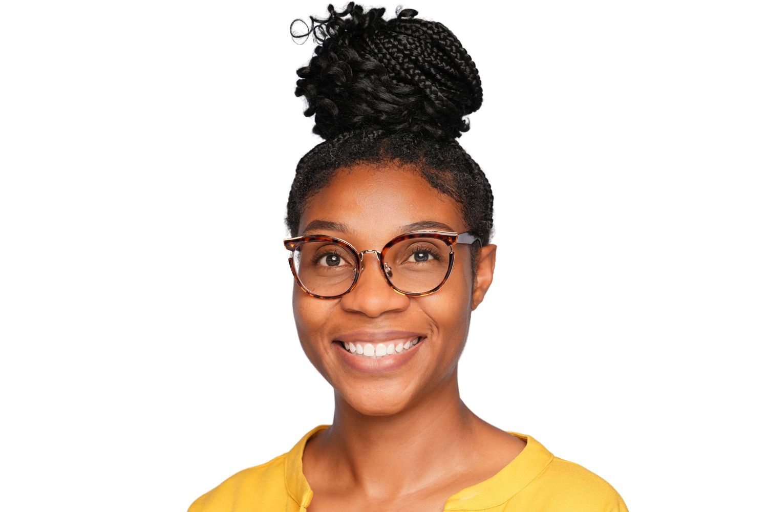 Smiling young woman with box braid updo and round glasses wearing a yellow top on white background.