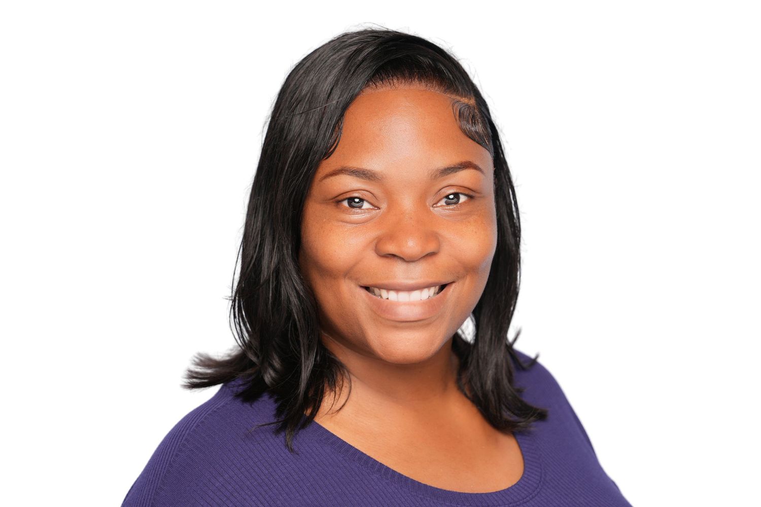 Smiling young woman with shoulder-length black hair wearing a purple top, professional headshot on white background.