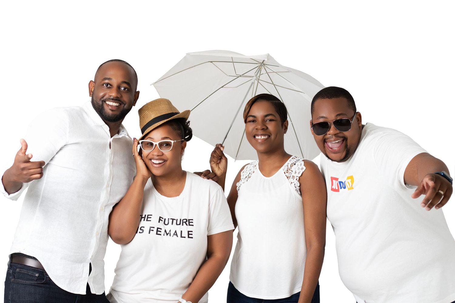 Four smiling people in white outfits pose together, one holding a white umbrella, against a white background.