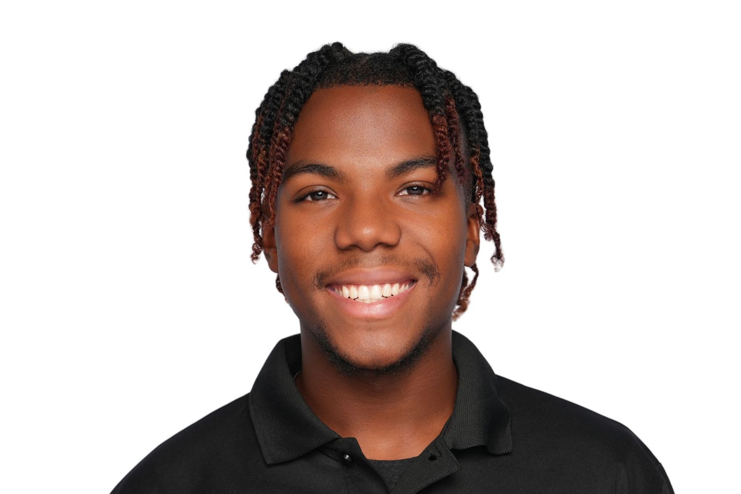 Young man with braided hair smiling, wearing a black polo shirt against a white background.
