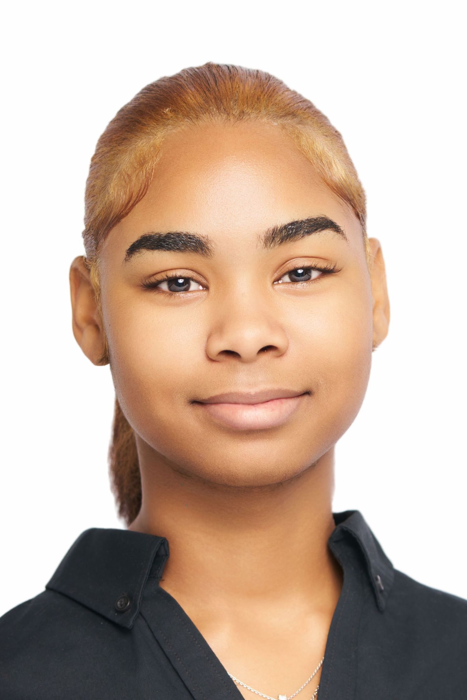 Young woman with blonde highlighted hair in a black shirt poses for a professional headshot on white background.
