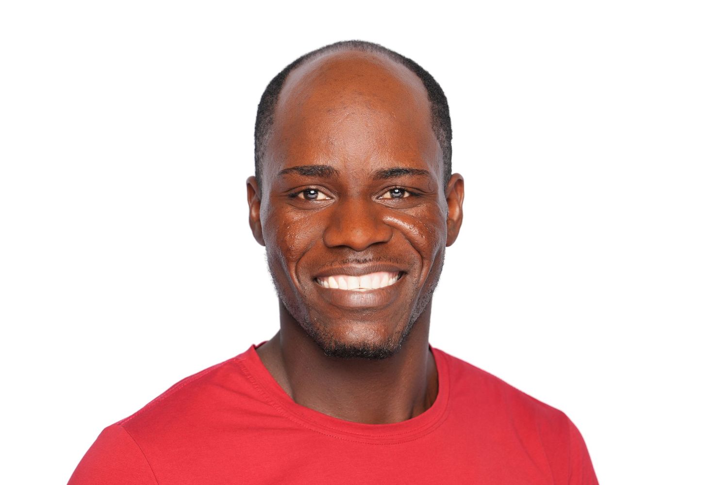Smiling young black man with a shaved head wearing a red t-shirt against a white background.