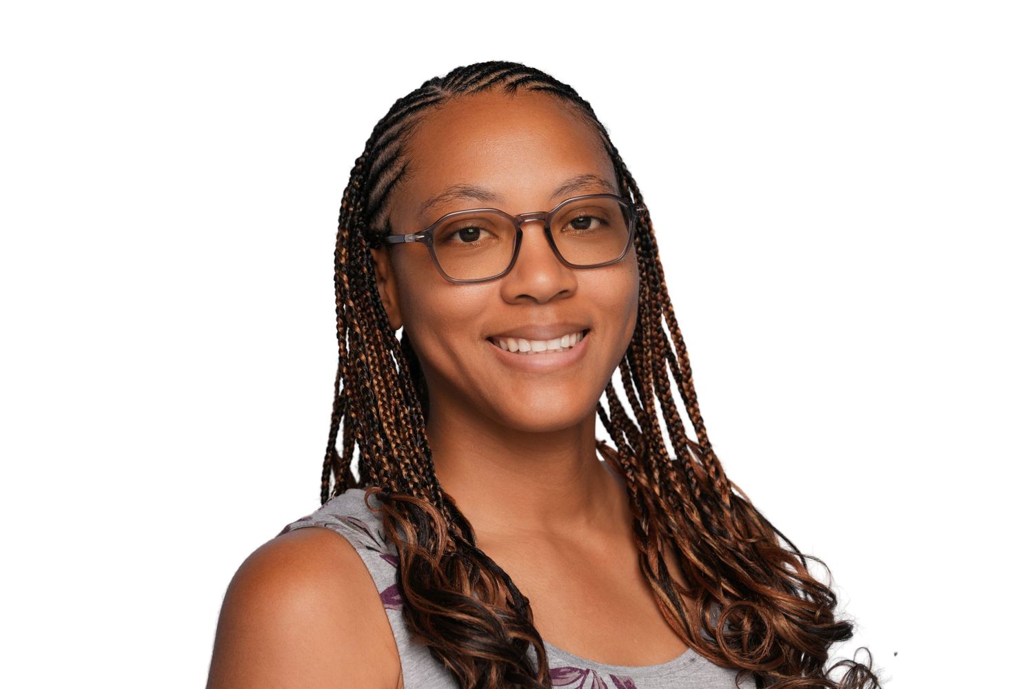 Smiling woman with braided hair and glasses wearing a sleeveless top against a white background.