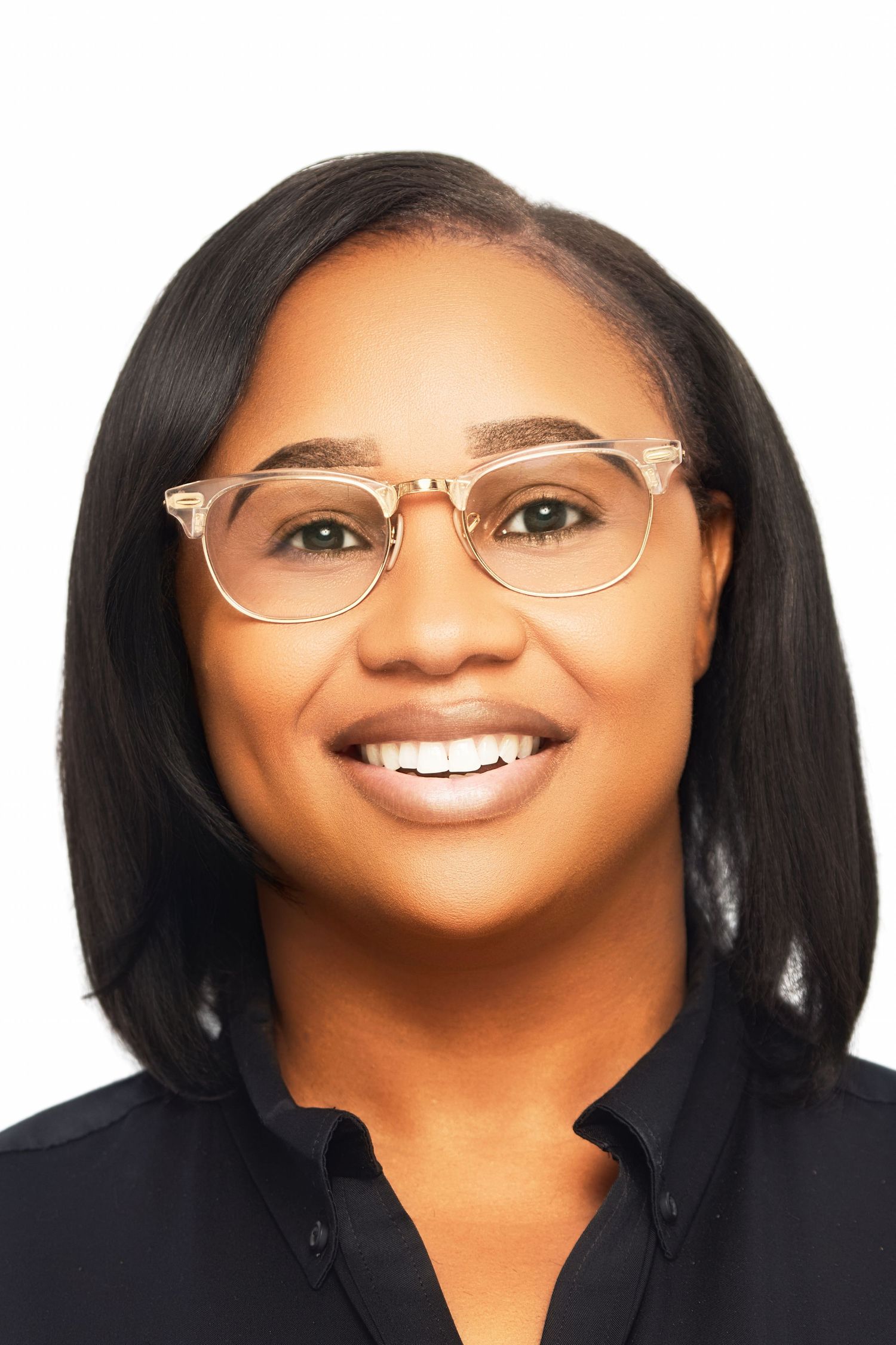 Smiling woman with glasses and black shirt poses for a professional headshot on white background.
