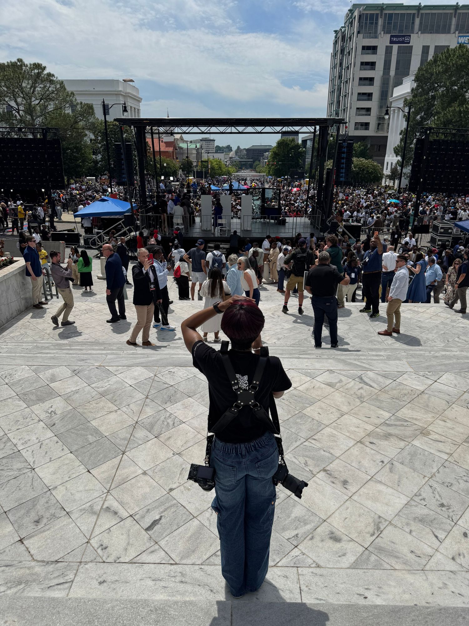 Photographer standing on marble steps capturing a large outdoor concert crowd and stage in Washington DC.