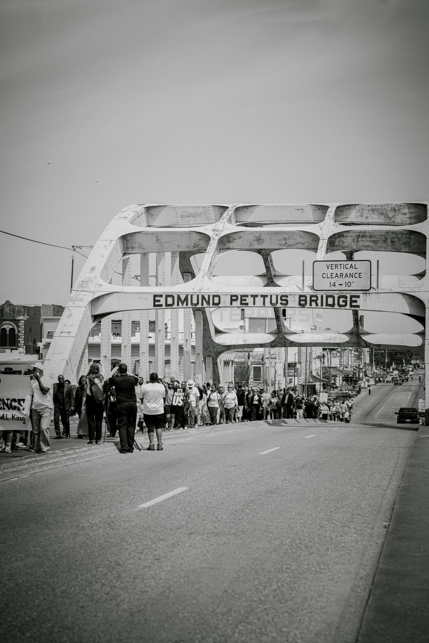 Crowds march across the historic Edmund Pettus Bridge in Selma Alabama in black and white.