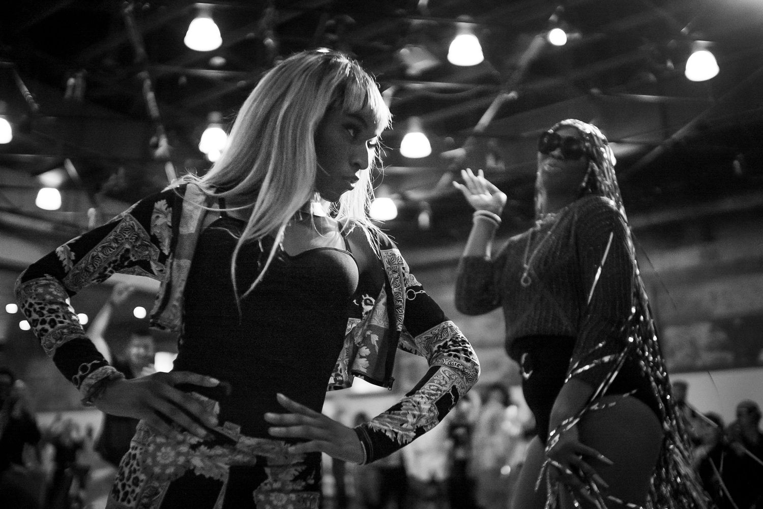 Black and white photo of two women dancing together at a vibrant indoor nightclub event.