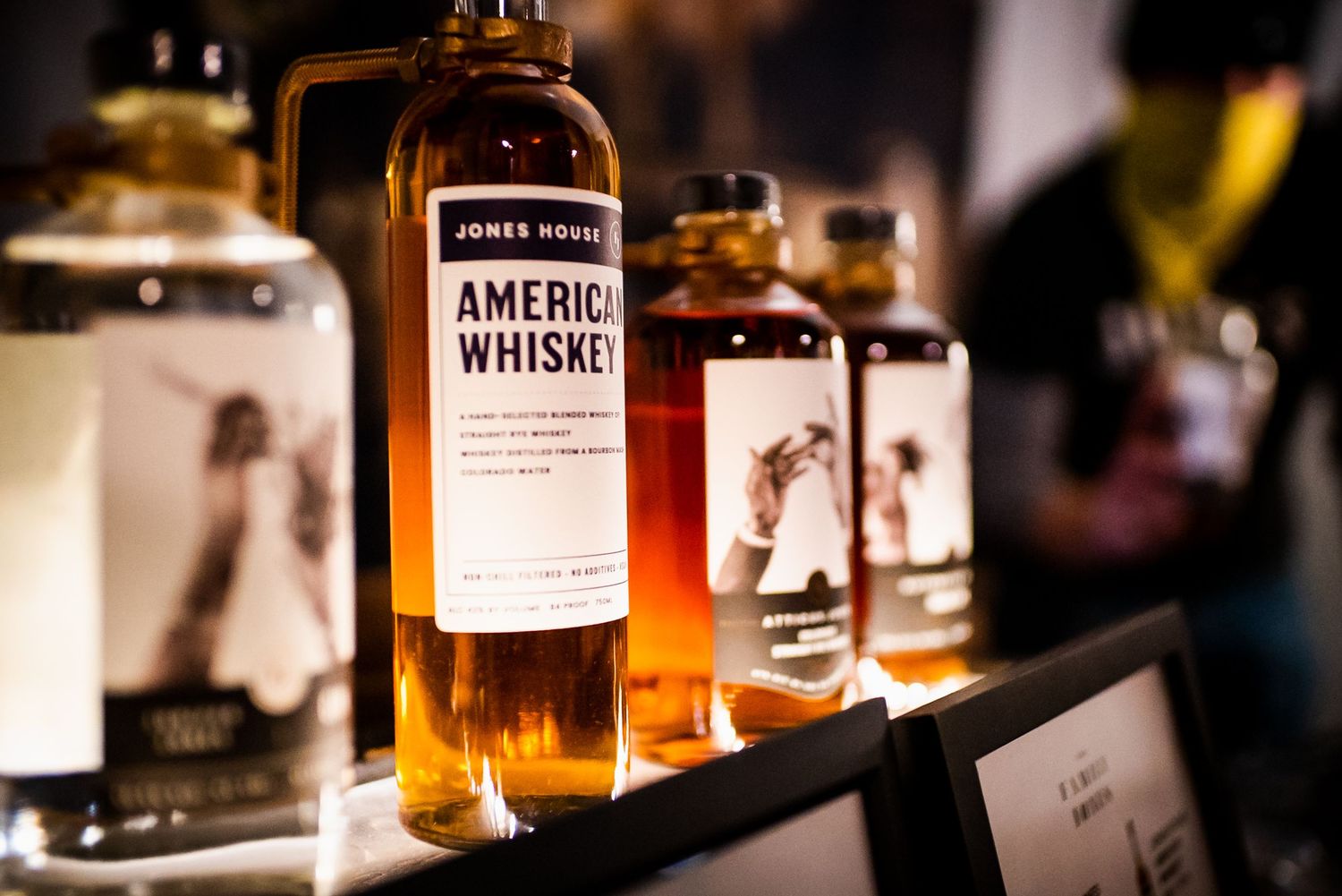 Jones House American Whiskey bottles displayed on a illuminated bar shelf.