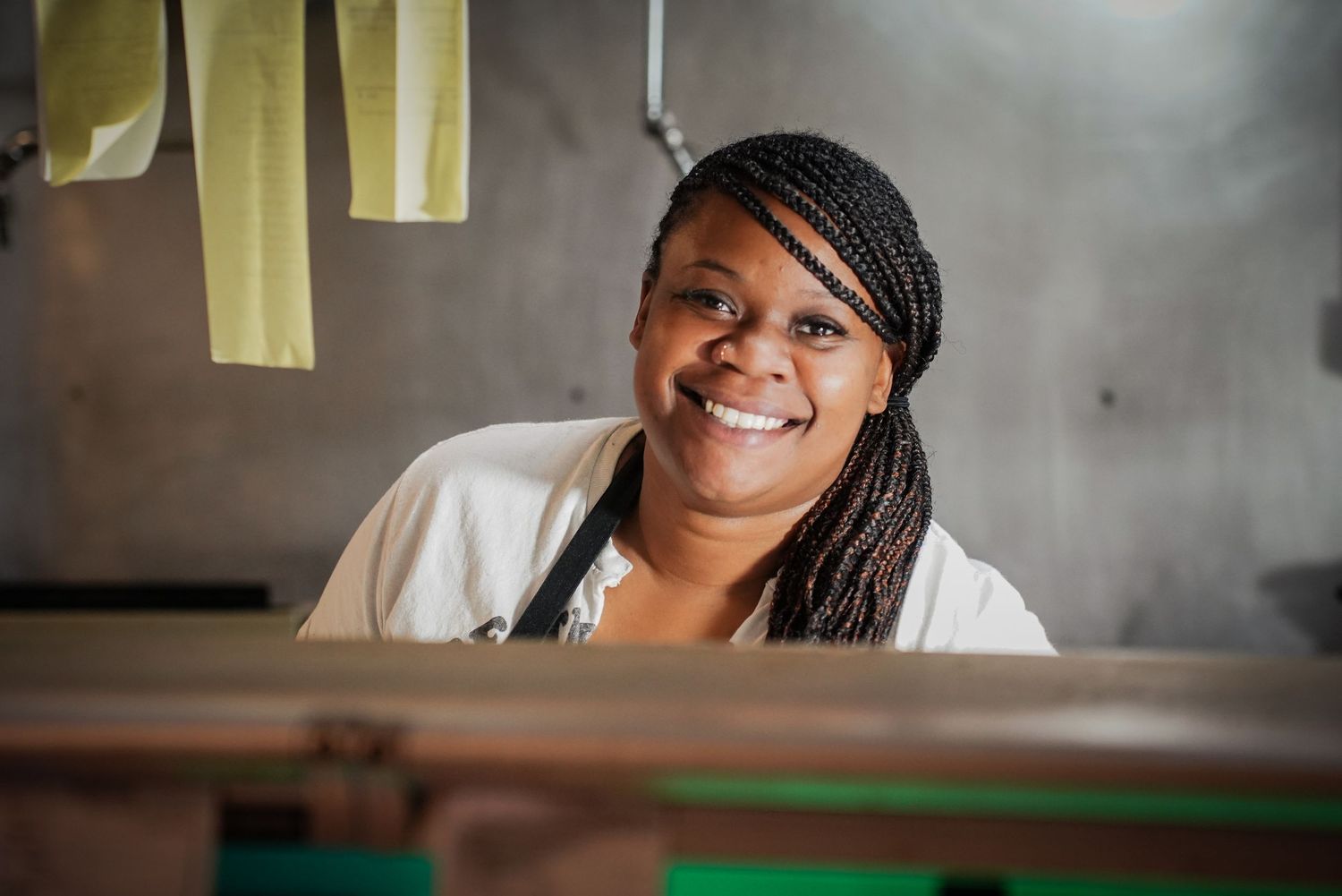 Smiling African woman with braids working at a loom in a textile workshop.