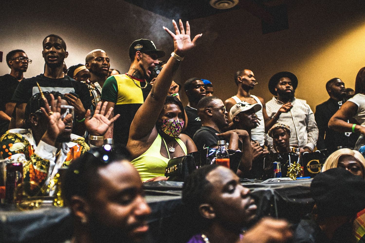 Energetic crowd of diverse people raising hands at a lively indoor cultural event or concert.