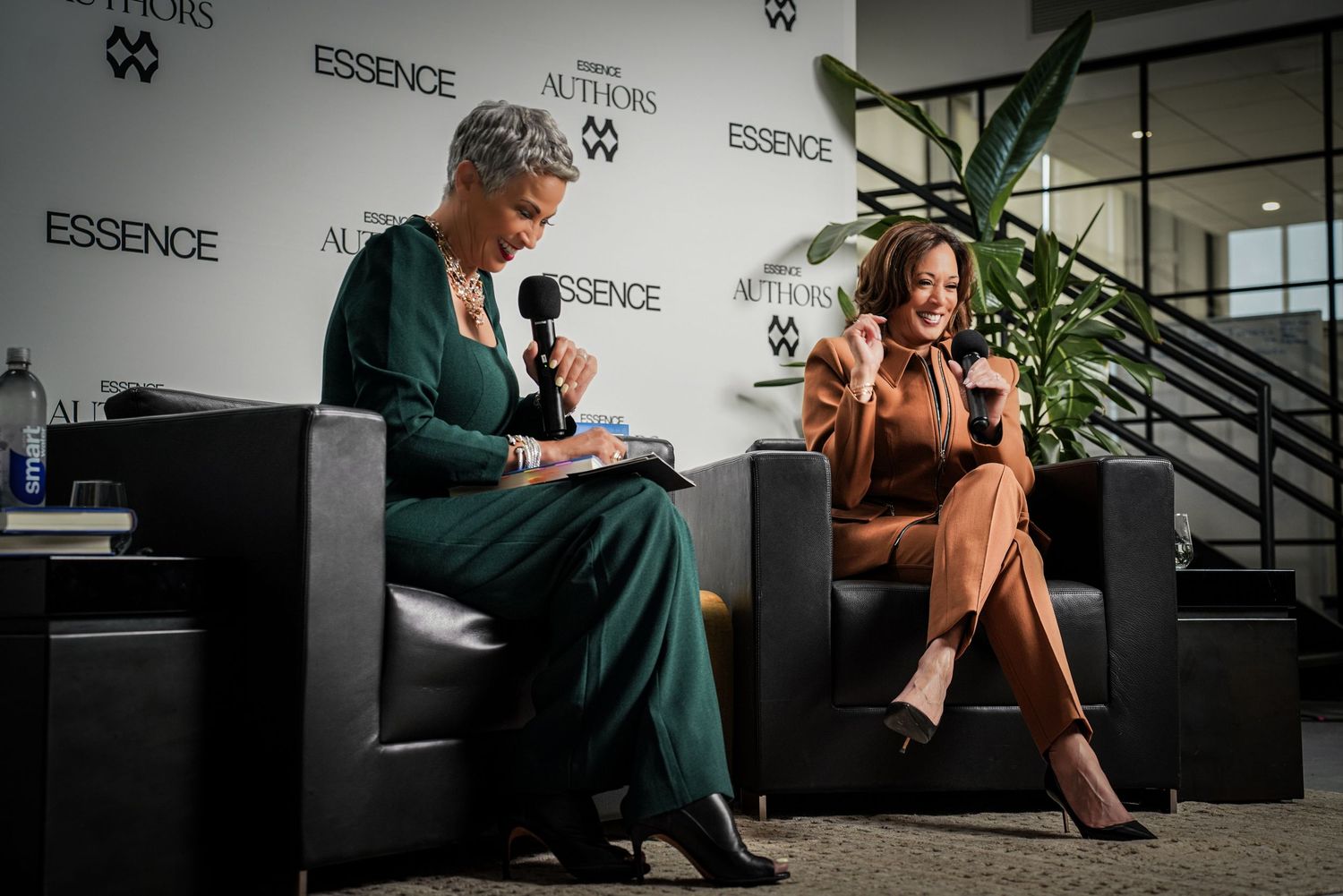 Two women in elegant outfits engaged in a conversation on stage at an Essence Authors event.