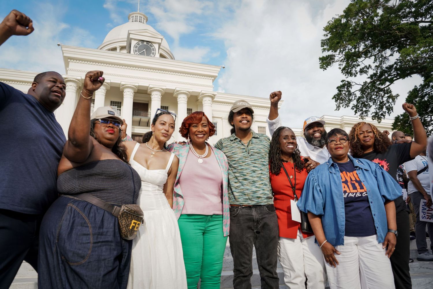 Group of Black activists raising fists in front of Alabama State Capitol building during civil rights demonstration.