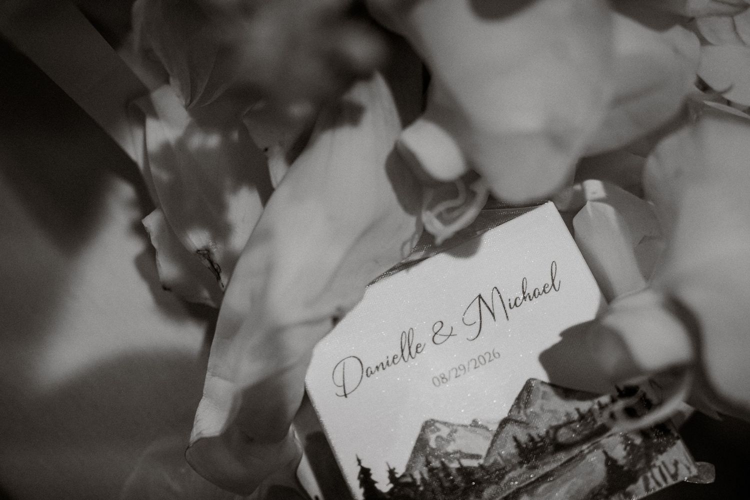 Black and white wedding card reading Danielle and Michael surrounded by elegant floral arrangements.