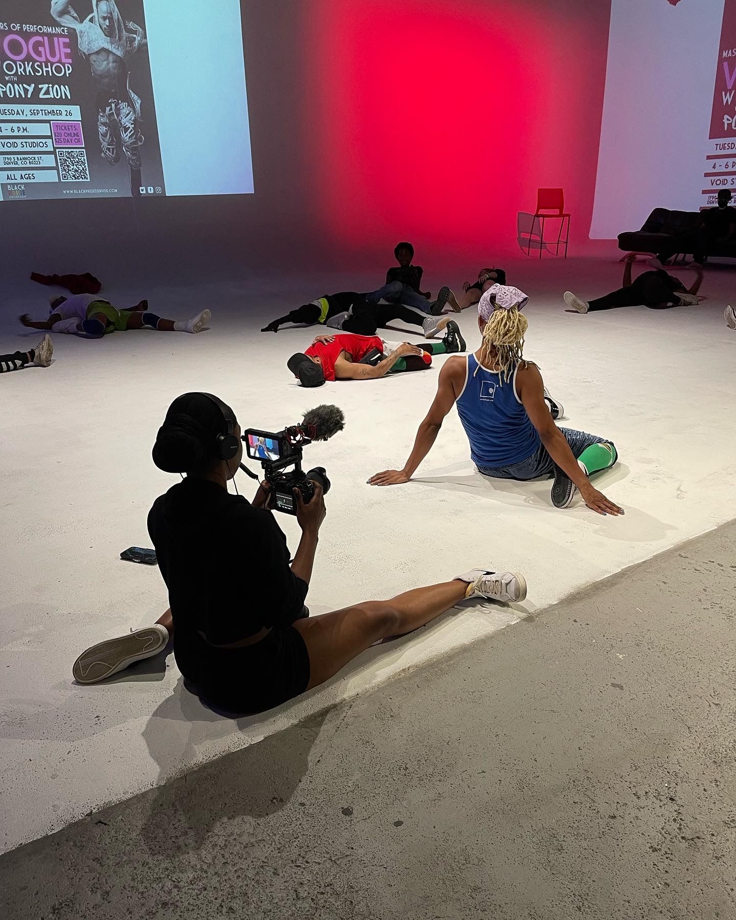 Videographer filming a dancer during a Vogue dance workshop performance in a modern studio space.