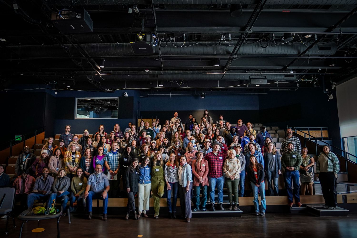 Large group of diverse conference attendees posing together for group photo in modern event venue.