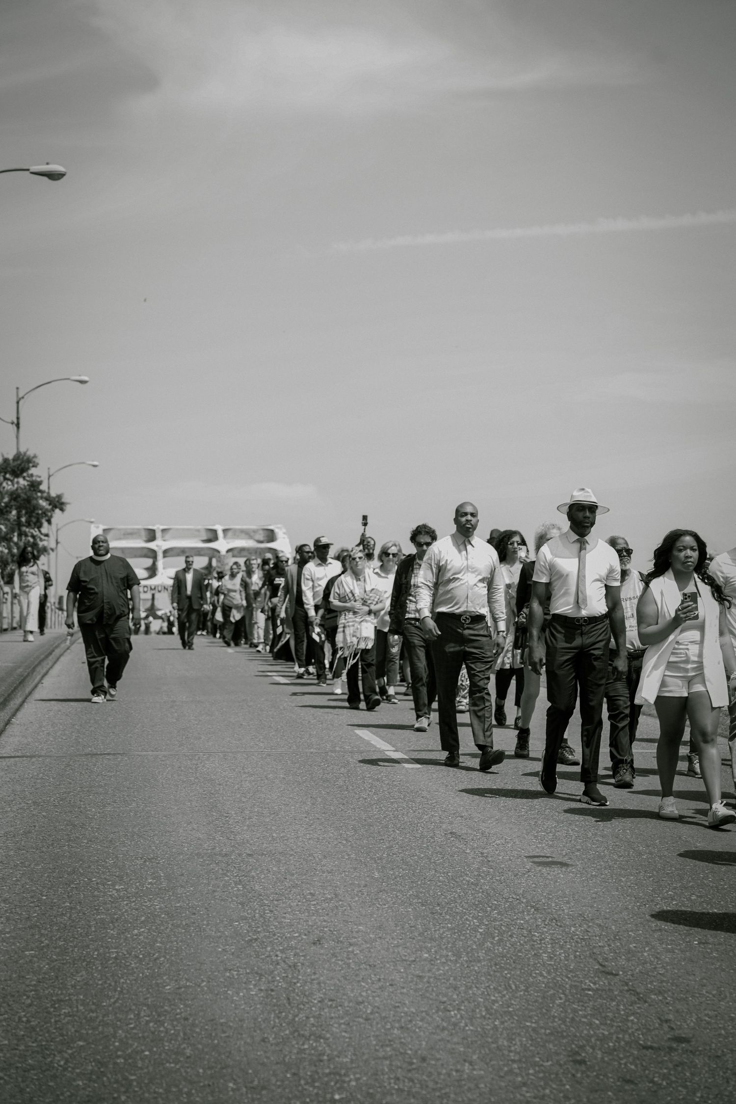 Large group of civil rights marchers walking across bridge in vintage black and white photograph.