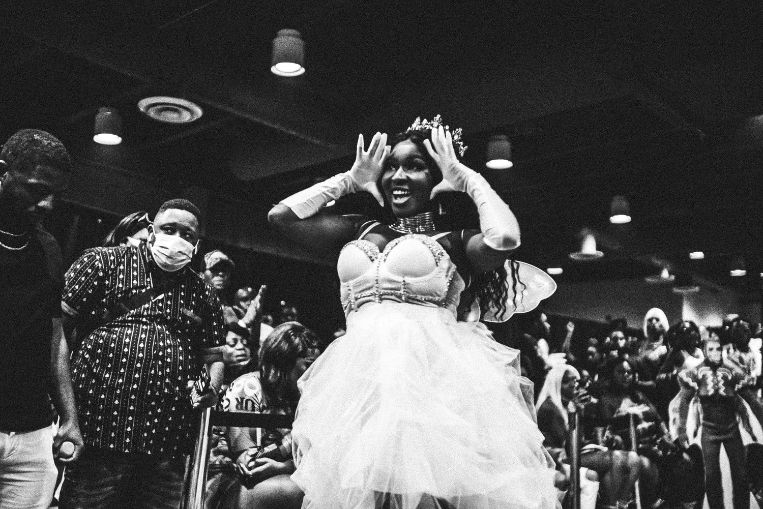Black and white photo of woman in white tulle dress celebrating joyfully at festive event.